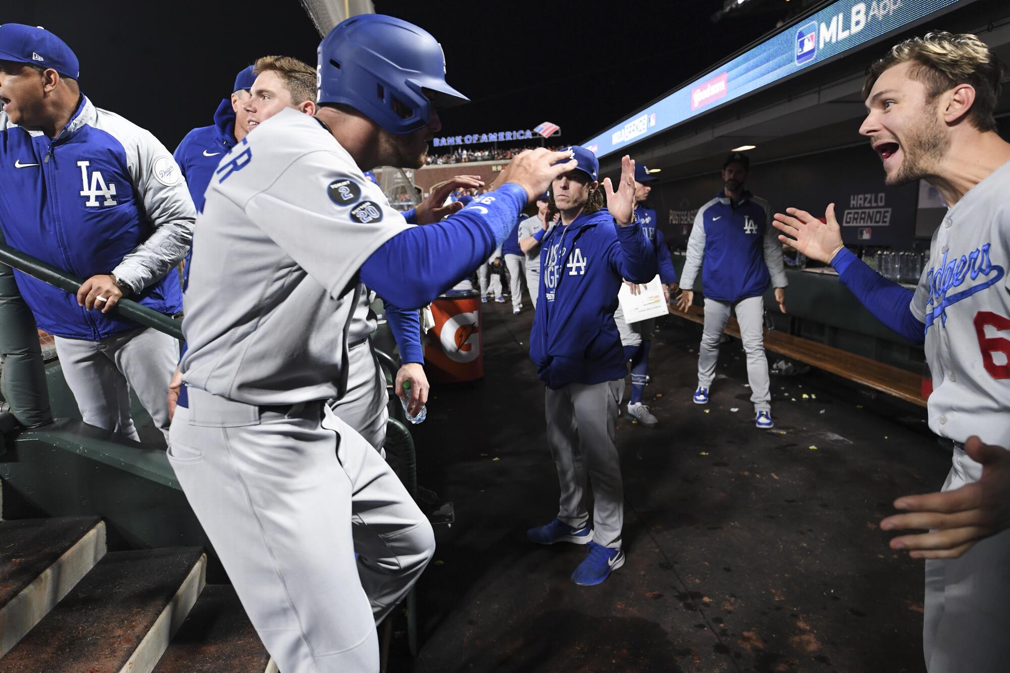 Los Angeles Dodgers' Cody Bellinger, left, celebrates with Trea Turner in the dugout after scoring