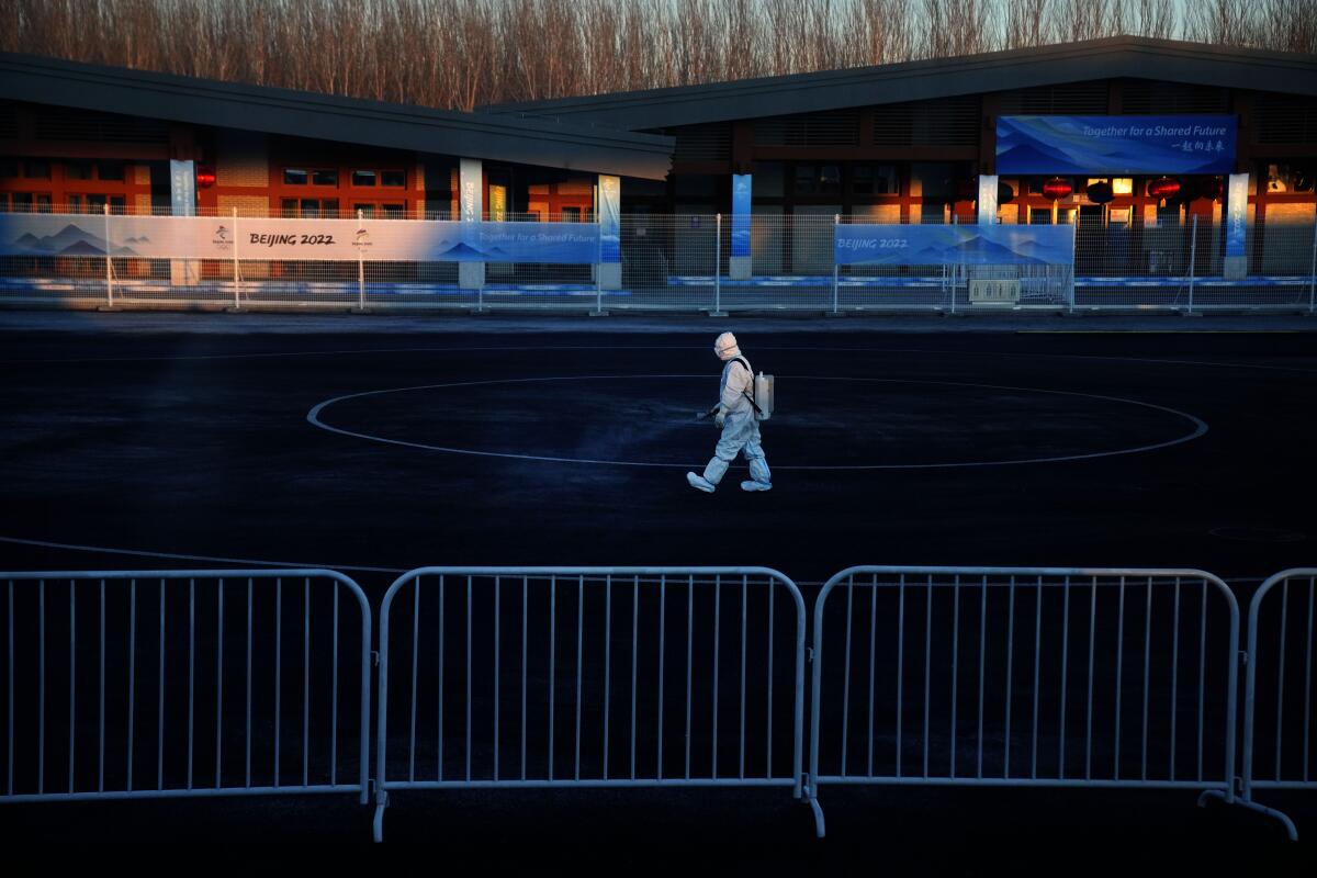 In a darkened arena, a person is seen in a full white protective suit.