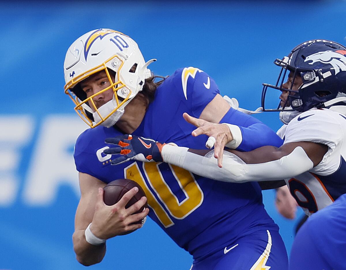 Chargers quarterback Justin Herbert is sacked by Broncos cornerback Ja'Quan McMillian.