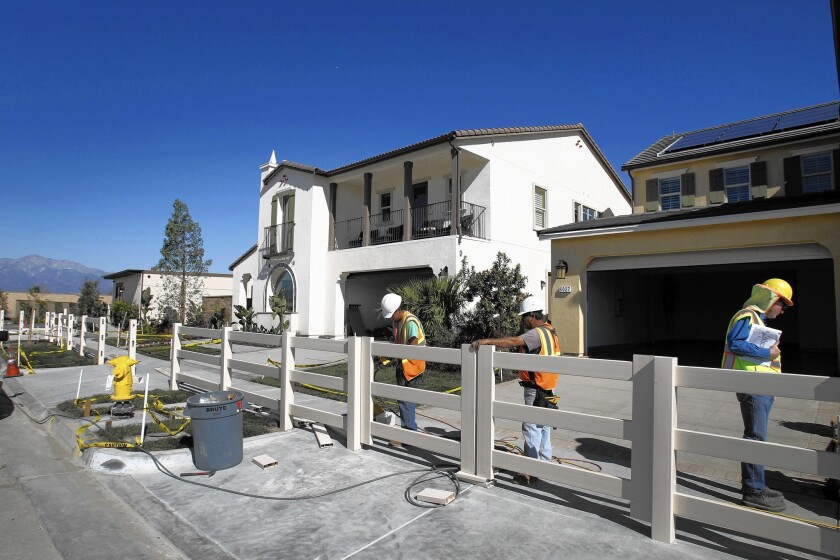 Construction crews work on model homes at the new Park Place housing community in Ontario.