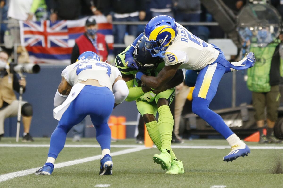 Seattle Seahawks wide receiver DK Metcalf, center, is tackled by Los Angeles Rams cornerback Jalen Ramsey as Rams' Taylor Rapp (24) moves in as Metcalf scores a touchdown during the first half of an NFL football game, Thursday, Oct. 7, 2021, in Seattle. (AP Photo/Craig Mitchelldyer)
