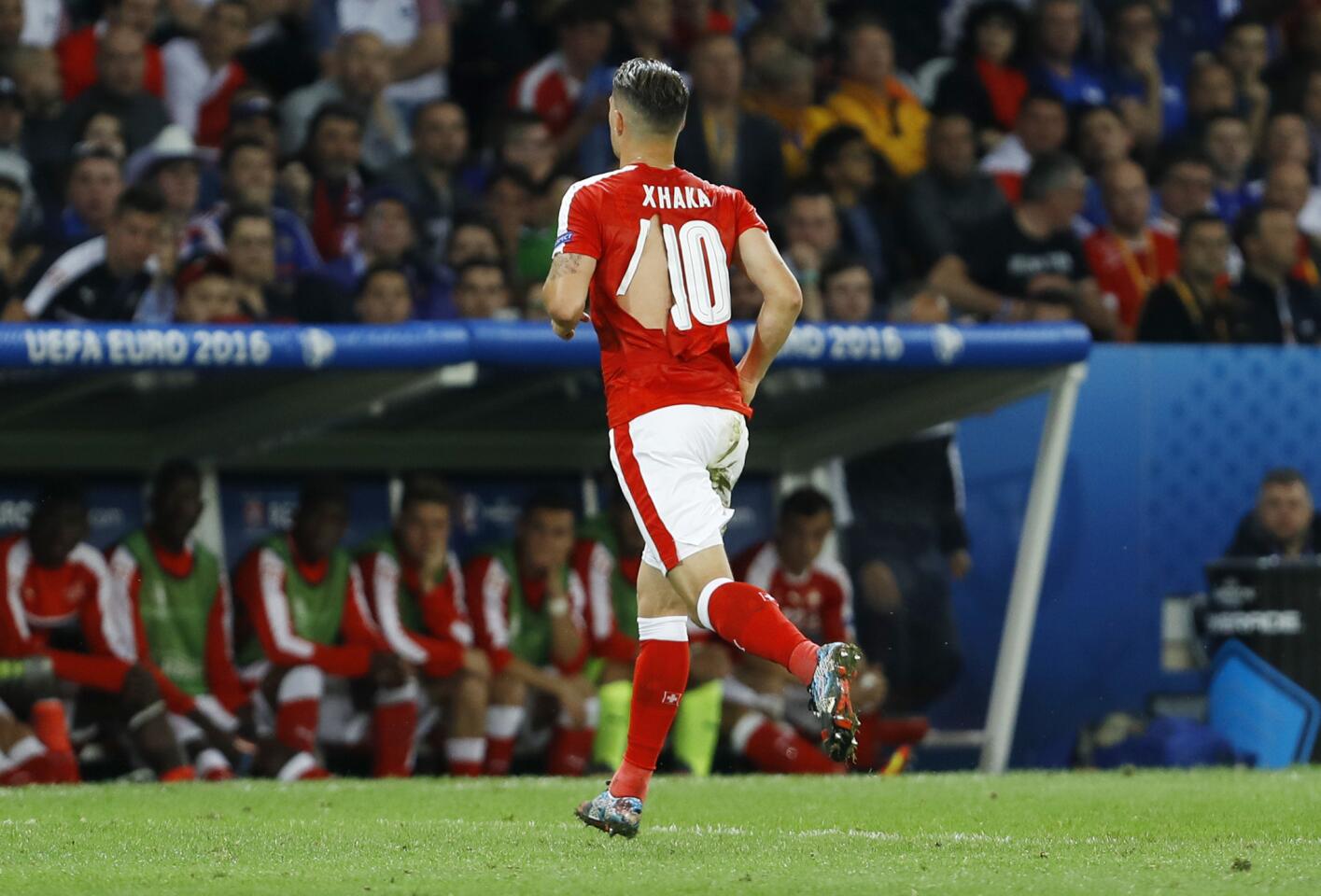 Switzerland's Granit Xhaka runs to the bench and change his ripped jersey during the Euro 2016 Group A soccer match between Switzerland and France at the Pierre Mauroy stadium in Villeneuve d'Ascq, near Lille, France, Sunday, June 19, 2016. (AP Photo/Darko Vojinovic)