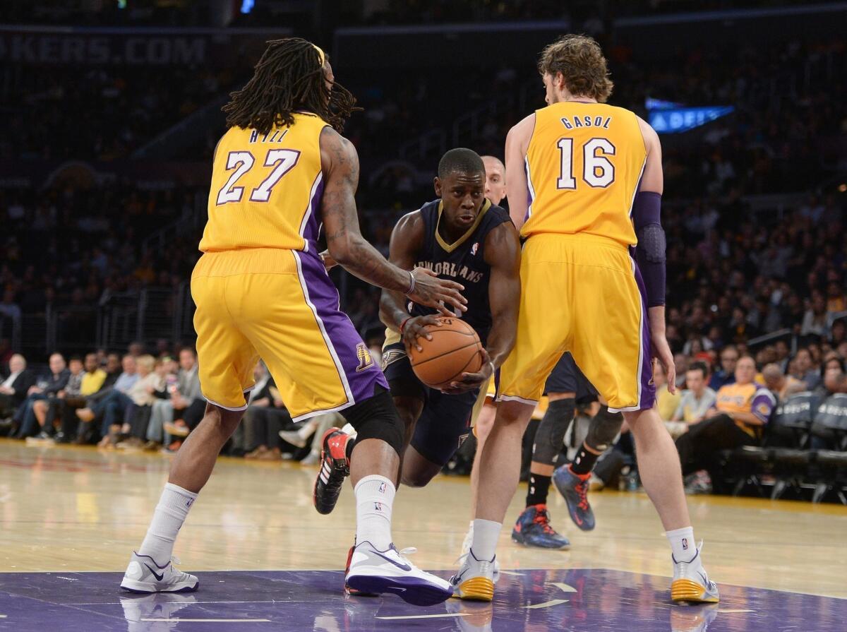 New Orleans' Jrue Holiday dribbles between Lakers Jordan Hill and Pau Gasol at Staples Center.