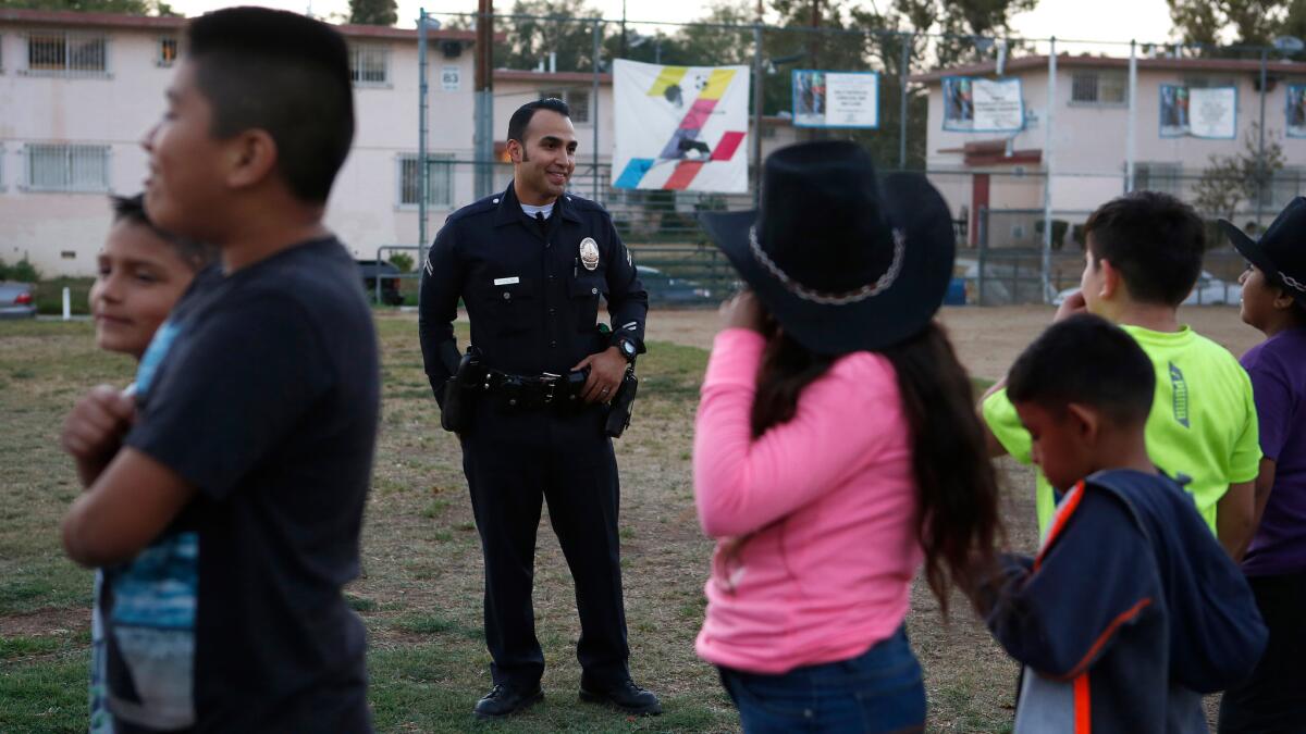LAPD Officer Jose Hidalgo talks with kids during a Summer Night Lights program at the Ramona Gardens Recreation Center in Boyle Heights.