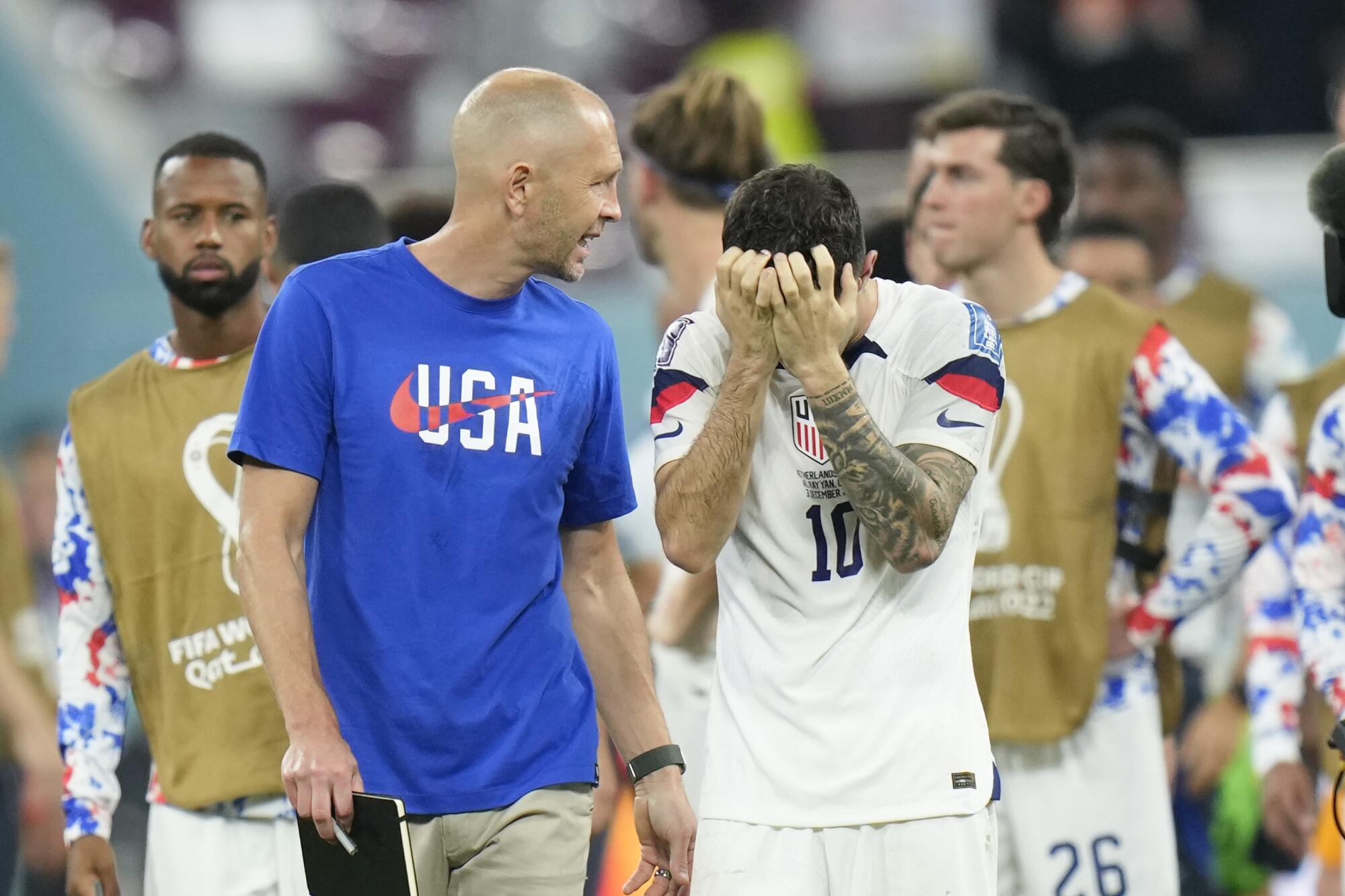 U.S. coach Gregg Berhalter turns to address someone while Christian Pulisic covers his face as they leave the field.