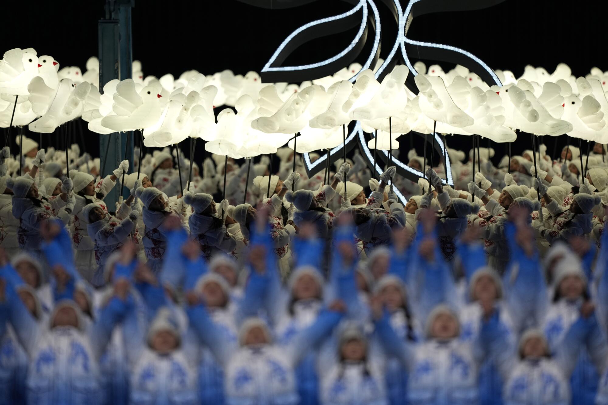 Children hold up images of doves during the opening ceremony.