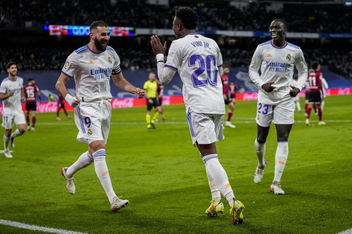 Real Madrid's Vinicius Junior, center, is congratulated by Real Madrid's Karim Benzema, left, after scoring his team second goal during the La Liga soccer match between Real Madrid and Valencia at Santiago Bernabeu stadium in Madrid, Spain, Saturday, Jan. 8, 2022. (AP Photo/Bernat Armangue)
