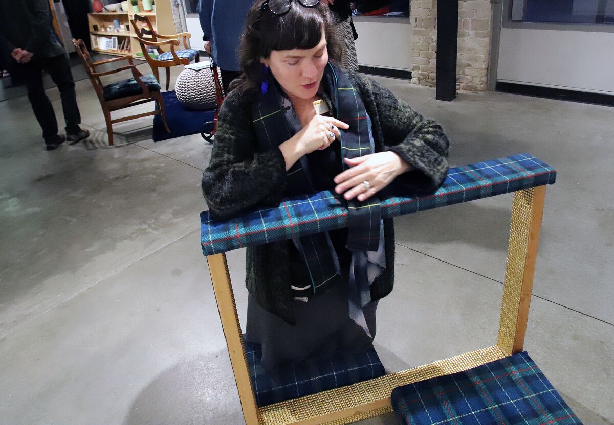 Artist Lexa Walsh kneels on a plaid kneeler. 