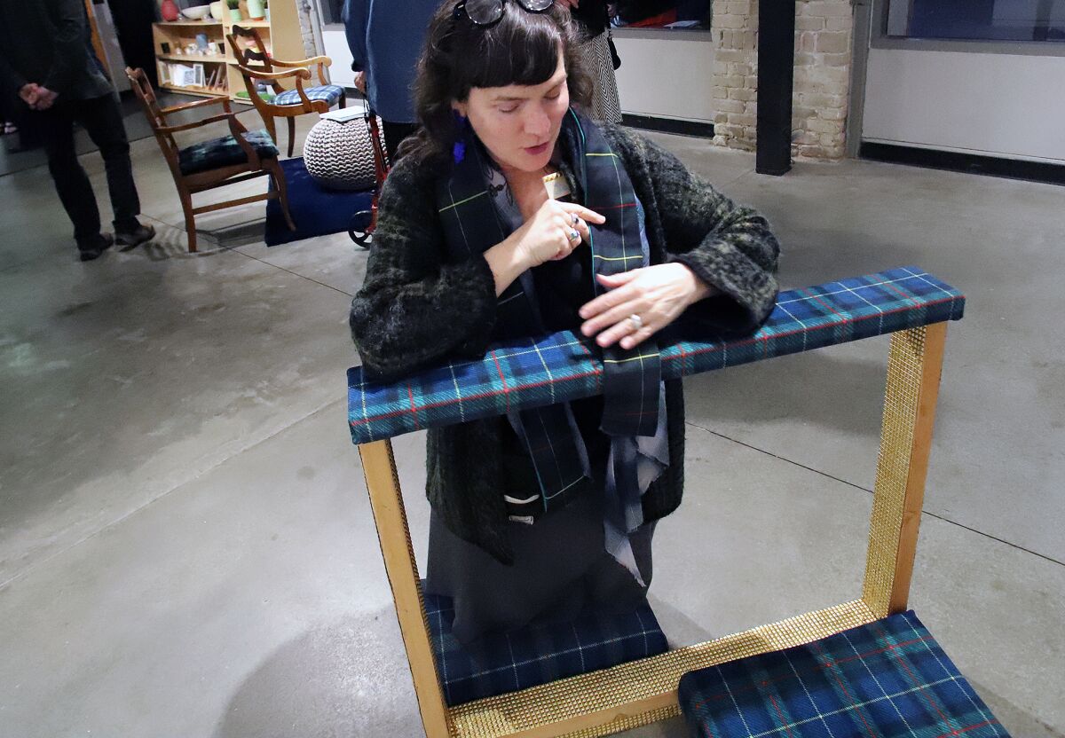Artist Lexa Walsh kneels on a plaid kneeler.