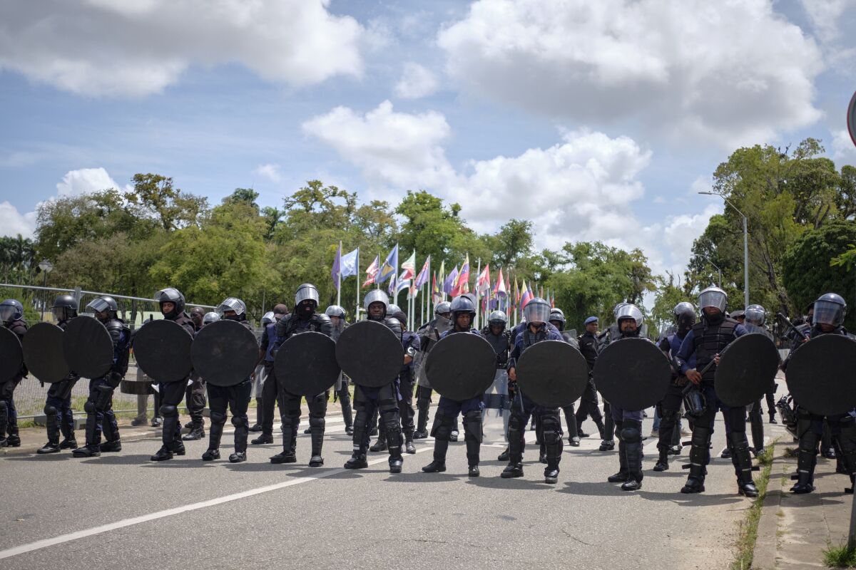 Security forces stand guard in the area of parliament on the sidelines of an anti-government protest in Paramaribo, Suriname, Friday, March 24, 2023. Protesters are demanding that the president resign. (AP Photo/Steve Tjin)