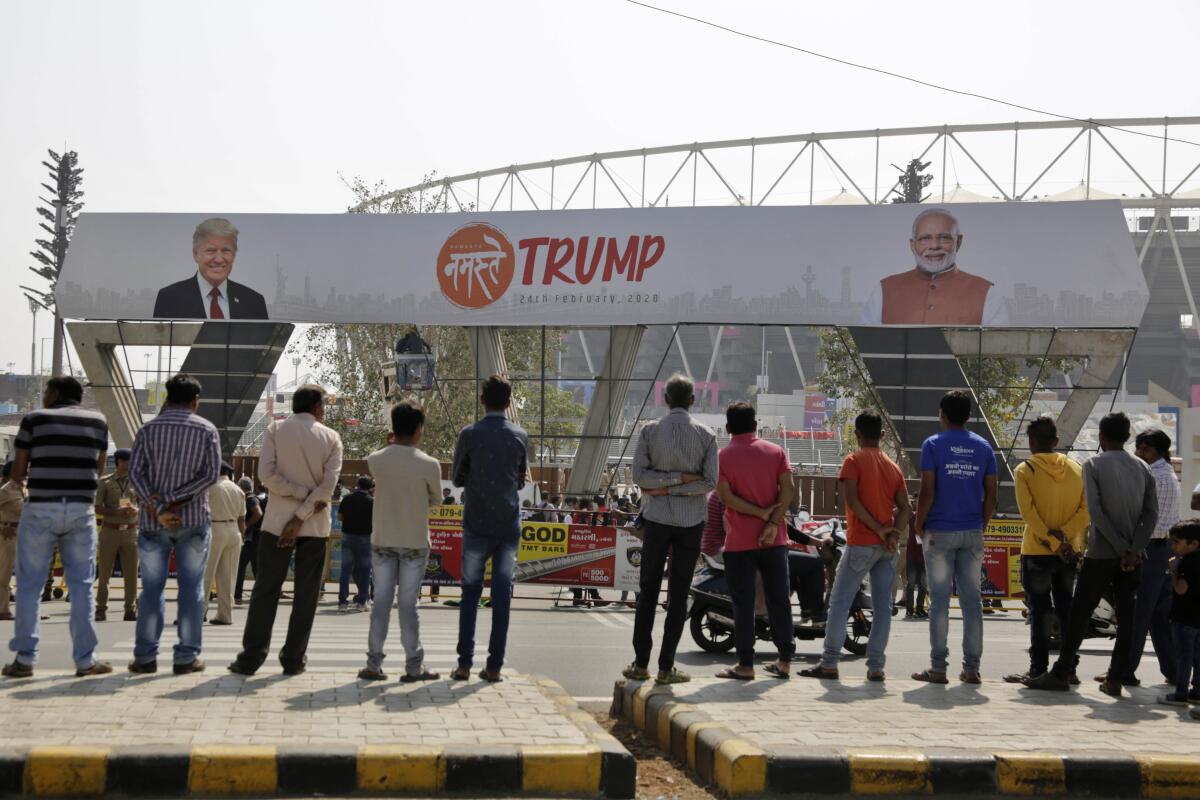 Workers fix a billboard at an entrance of Motera cricket stadium before President Trump's visit to Ahmedabad, India.