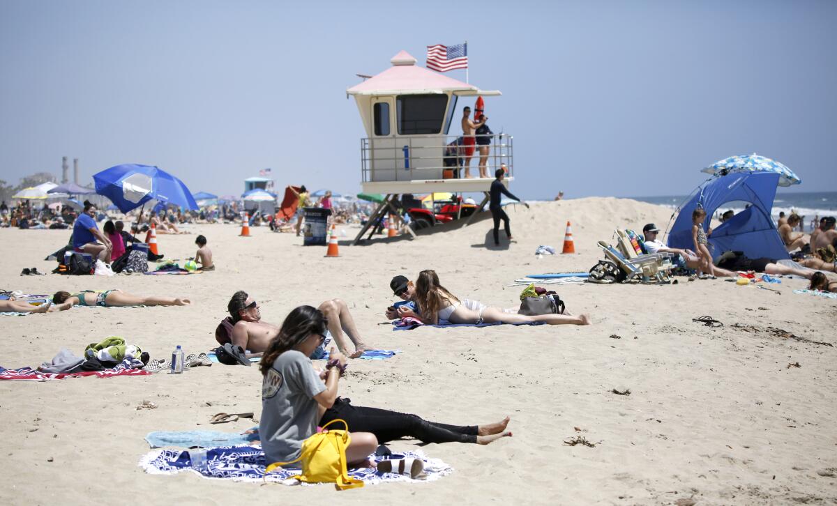 Beachgoers sunbathe in Huntington Beach on May 23. A man was found dead at the beach on Tuesday.