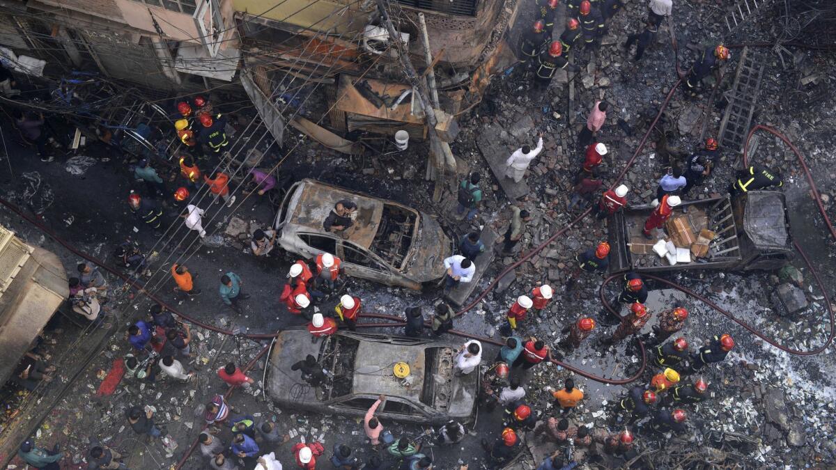 Rescuers stand at the site of a devastating fire that raced through buildings in an old part of Bangladesh's capital and killed scores of people.