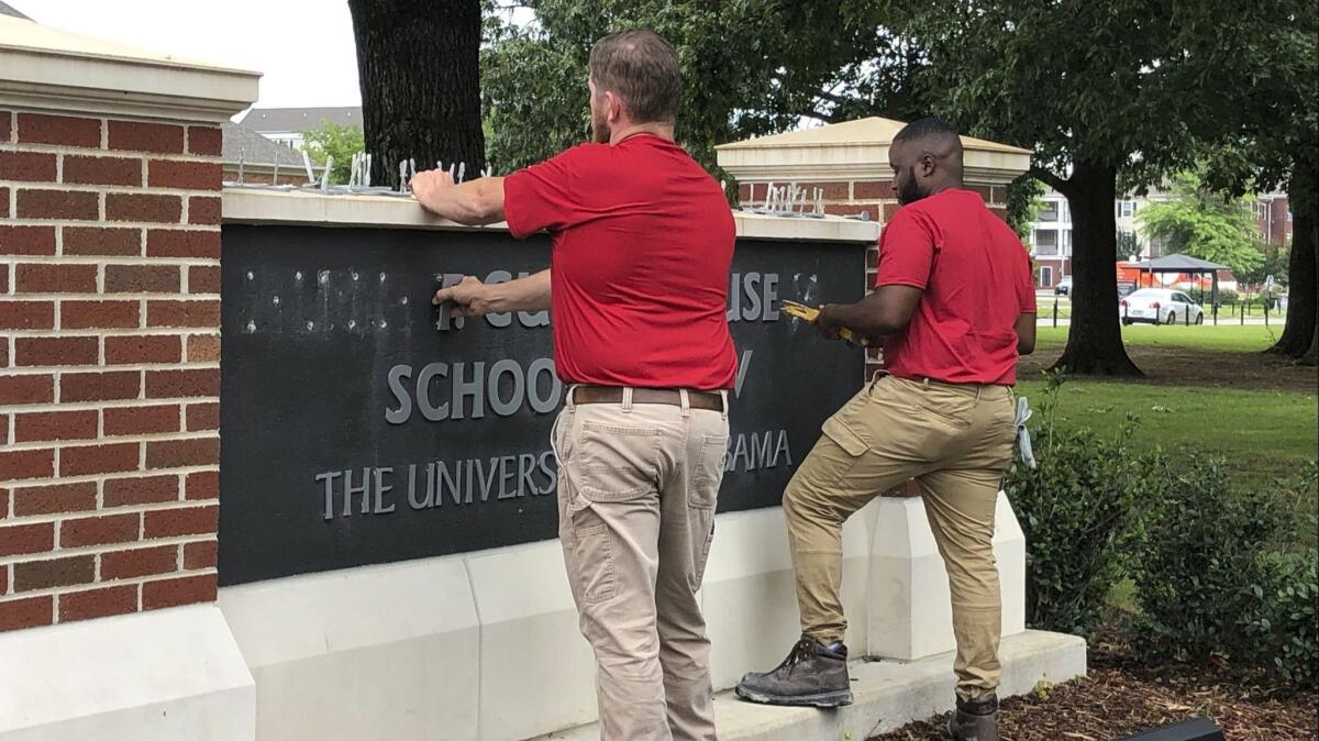 University of Alabama employees remove the name of Hugh F. Culverhouse Jr. off the School of Law sign in Tuscaloosa, Ala., on Friday.