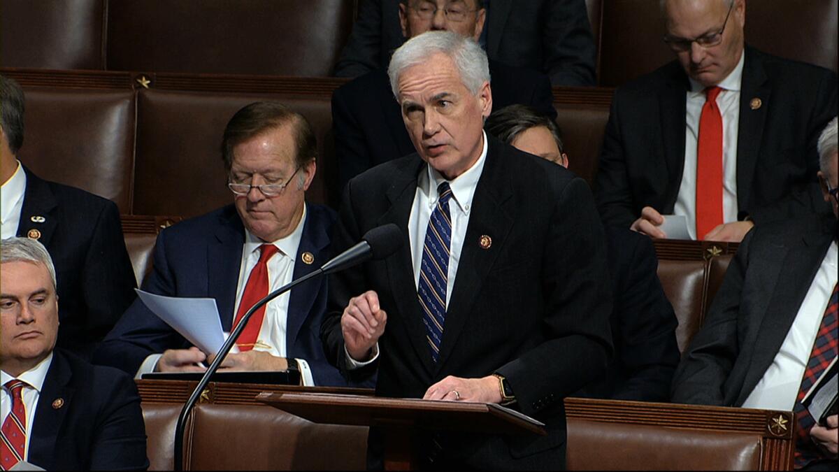 Tom McClintock speaking at a lectern in the House as other lawmakers sit nearby
