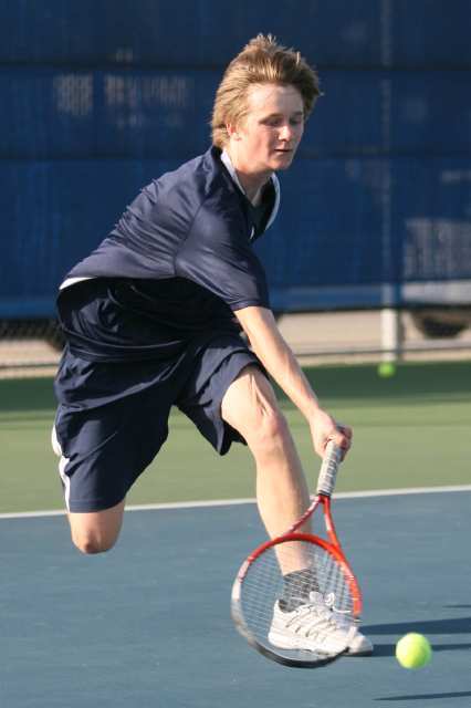 Newport Harbor's Troy Arnold hits a shot low off the court during Thursday's Battle of the Bay tennis match between Corona del Mar and Newport Harbor.