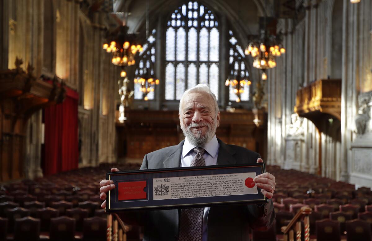 Stephen Sondheim poses a framed certificate in the Gothic architecture of London's Guildhall 