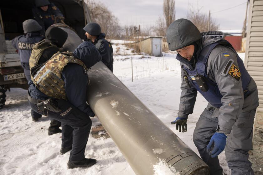 Ukrainian emergency services employees push the remains of an S-300 missile fired by Russian forces onto a truck in Kharkiv, Ukraine, Friday, Feb. 17, 2023. Russia pummeled Ukraine with a barrage of cruise and other missiles on Thursday, hitting targets from east to west as the war's one-year anniversary nears, one of the strikes killed a 79-year-old woman and injured at least seven other people, Ukrainian authorities said. (AP Photo/Vadim Ghirda)