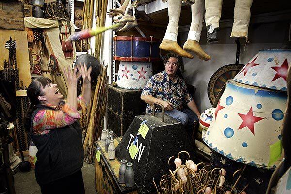 Jim Elyea tosses a juggling club to his wife Pam while gathering props for the film "Water for Elephants" at their store, History for Hire, in North Hollywood. The company has been in business for 25 years, renting out historically accurate props.