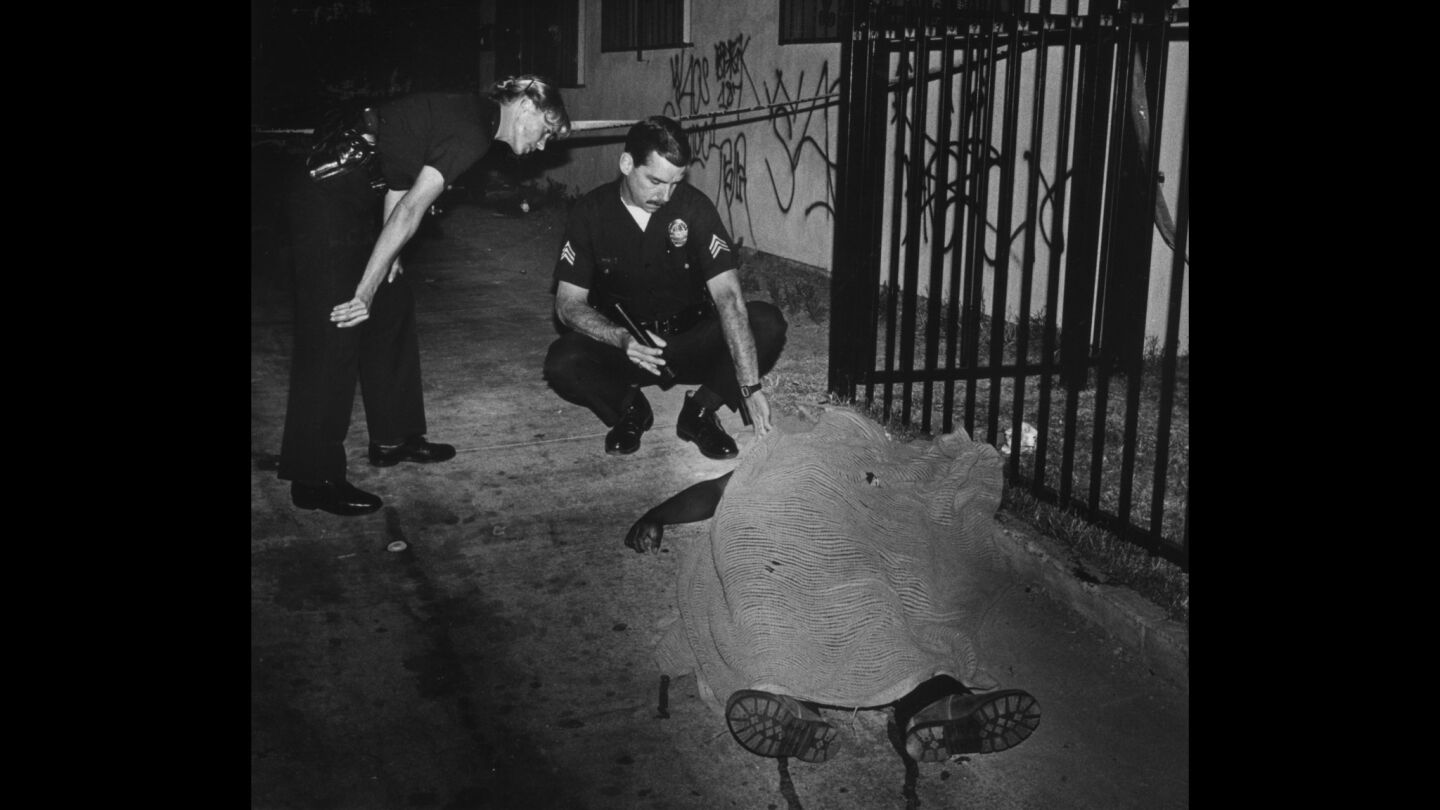 LAPD Sgt. J. J. Reese, right, and another officer examine the body of Charles "C.C." Ticer, a Five Deuce Hoover Crip killed in a drive-by shooting.