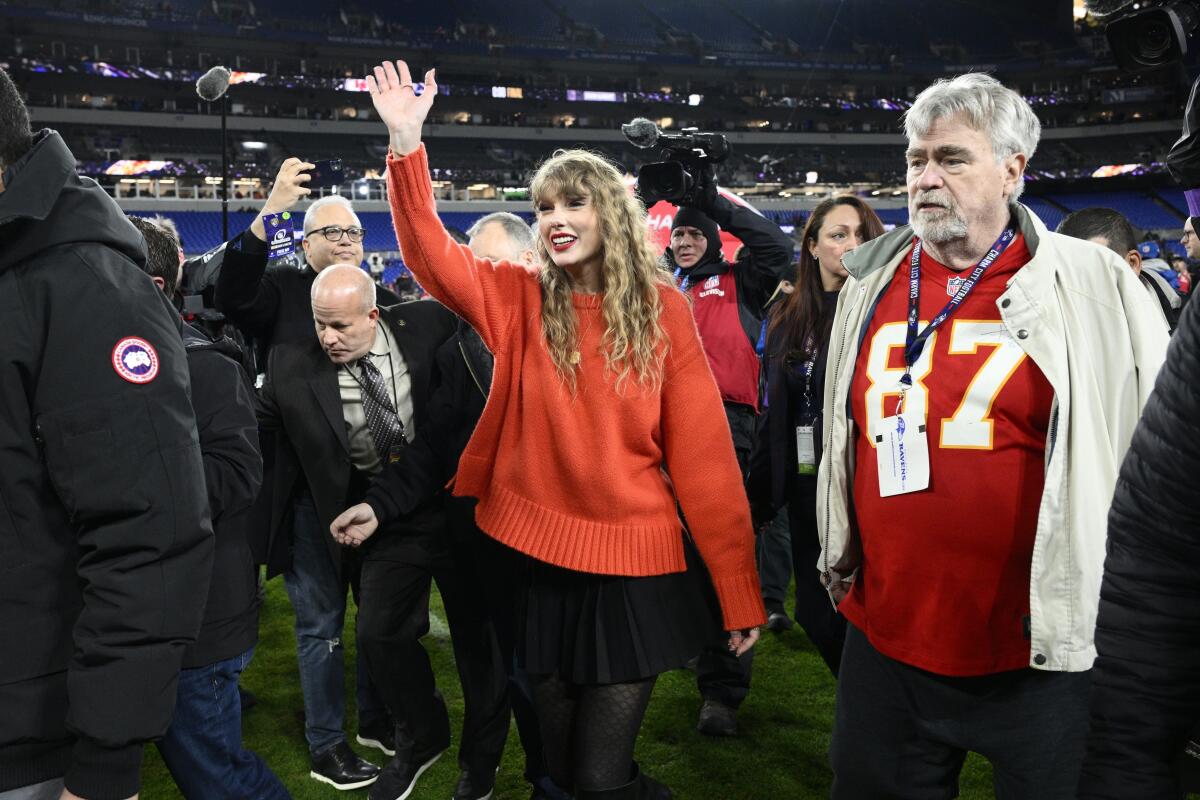 Taylor Swift waves as she walks with Ed Kelce after the AFC championship game.