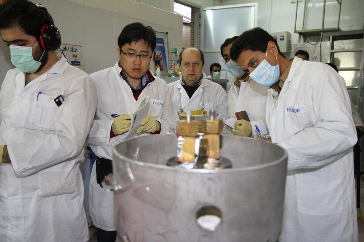 International Atomic Energy Agency inspectors monitor Iranian technicians as they disable equipment at the Natanz uranium enrichment facility.