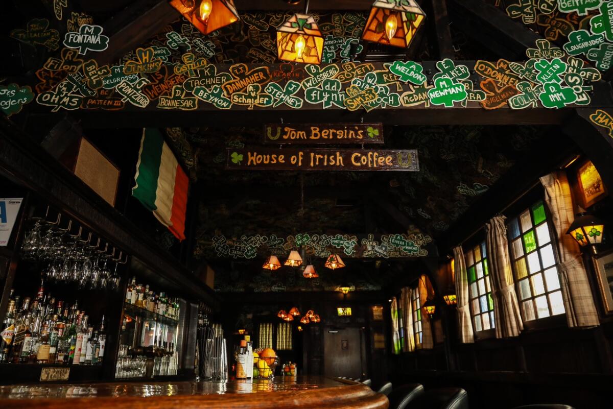 The interior of a dark bar with paper shamrocks on the ceiling and stained-glass light fixtures