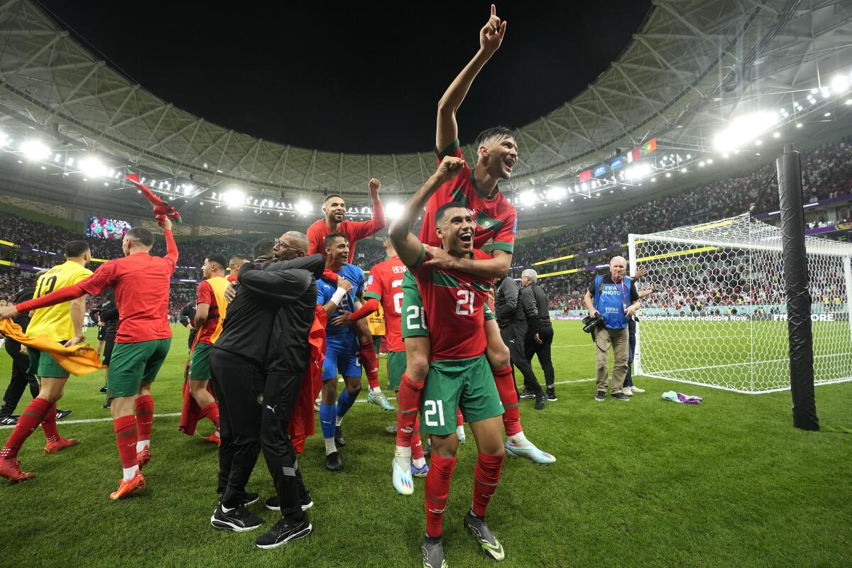 Morocco's players jump on each other and raise their fists after winning the World Cup quarterfinal match against Portugal.