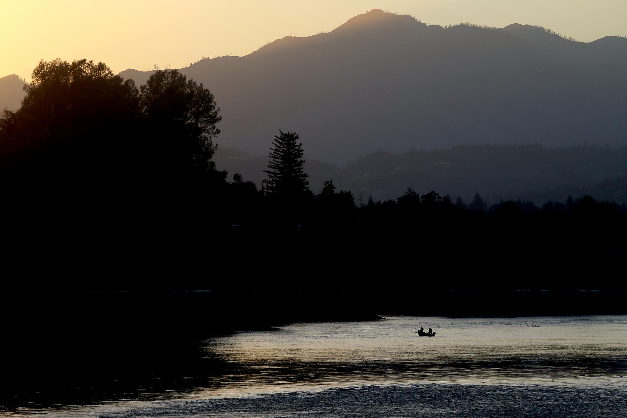 Anglers in a boat cast lines into a river.