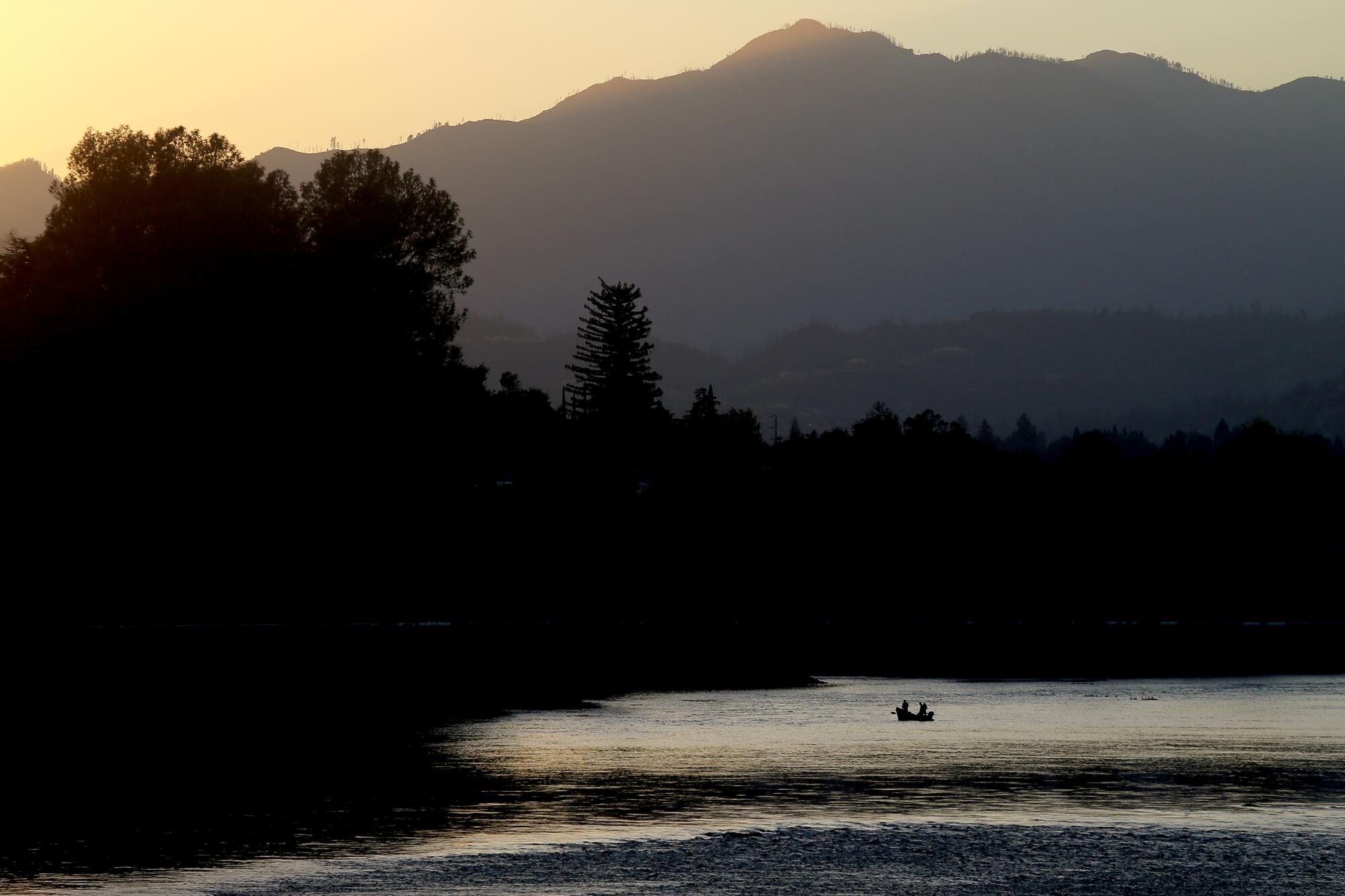 Anglers in a boat cast lines into a river.  