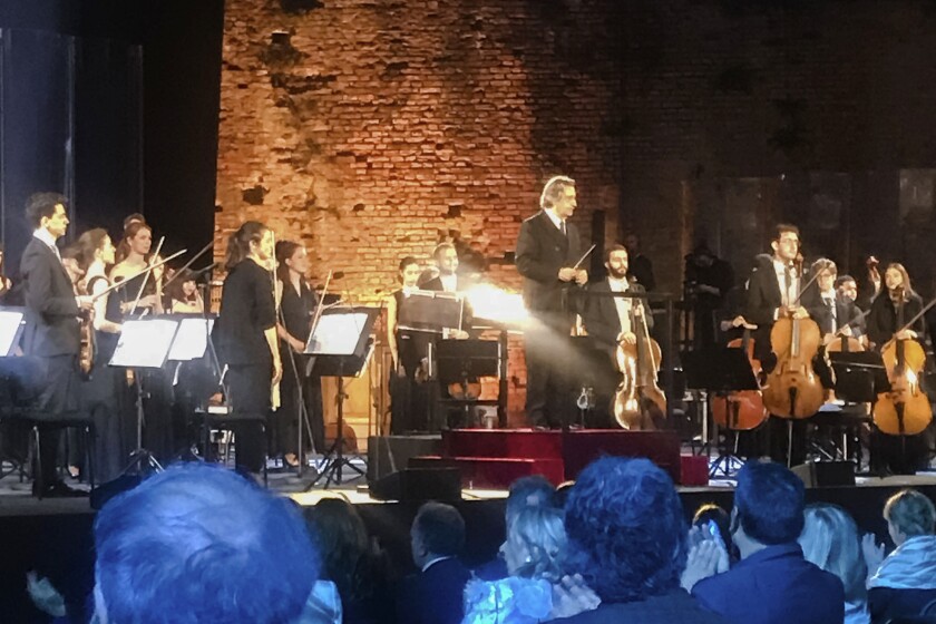 FILE - In this June 21, 2020 file photo, Italian Maestro Riccardo Muti, top center, prepares to direct a concert at the Ravenna Festival, in Ravenna, Italy. With a purposeful nod and flick of his baton, the 79-year-old conductor on Sunday, May 9, 2021, ended what has been an unexpectedly long silence in Italian theaters, enrapturing a socially distanced and masked audience with the Vienna Philharmonic Orchestra’s first live performances since fall, two evening concerts of Mendelssohn, Schumann and Brahms, in his adopted hometown of Ravenna. (AP Photo/Colleen Barry, file)