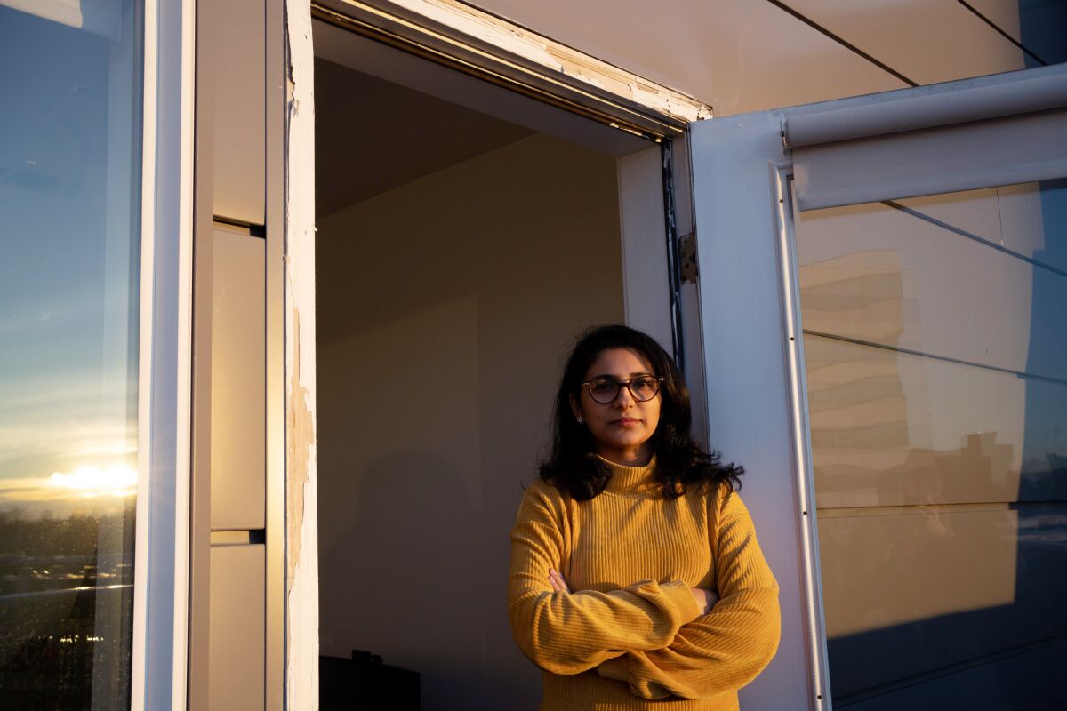 woman in a yellow shirt stands in a doorway
