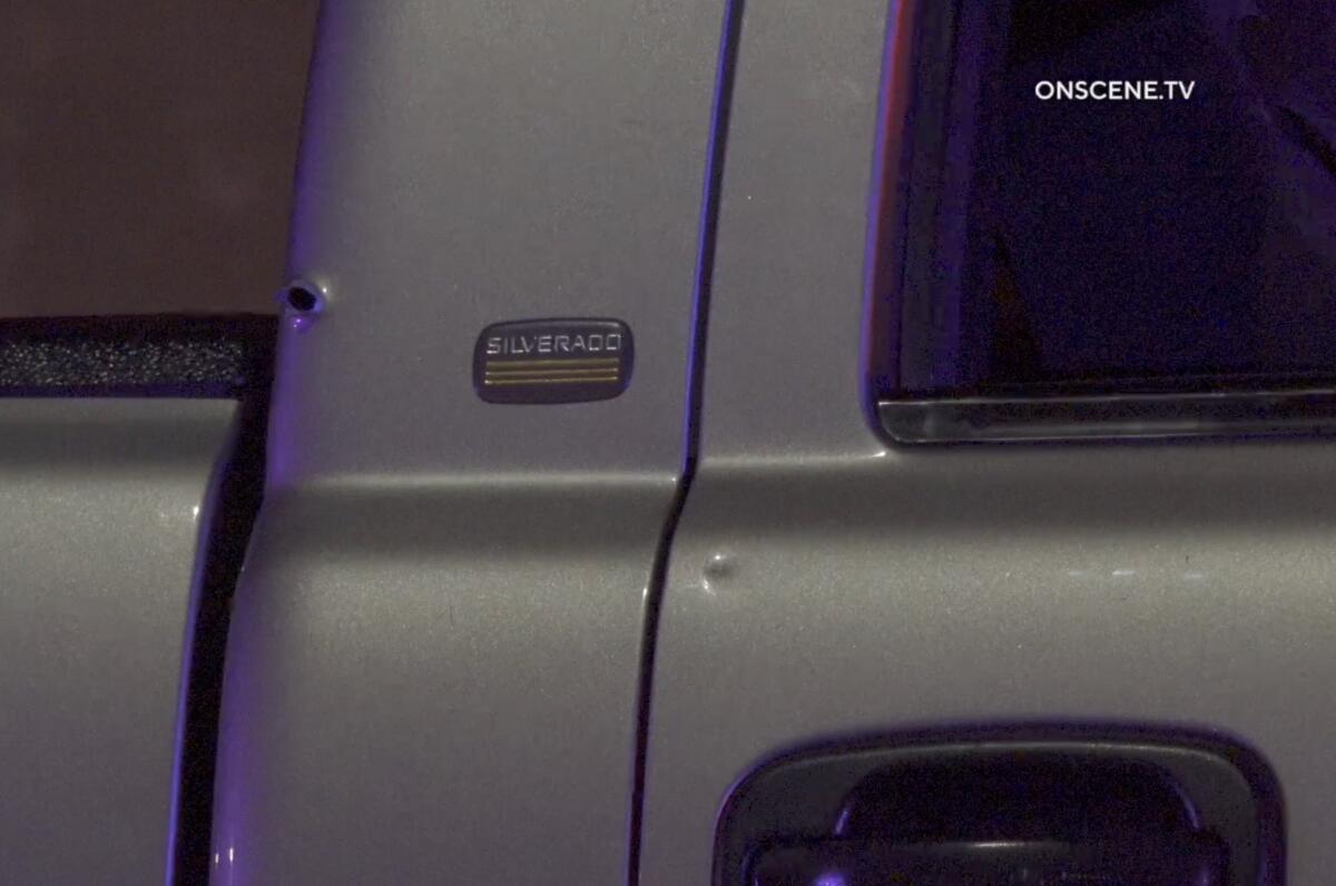 A bullet hole is seen in the side of a pickup truck.