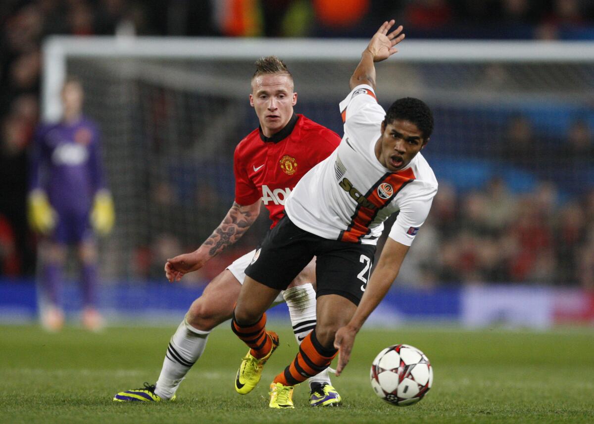 Donetsk's Douglas Costa, right, gets away from Manchester United's Alexander Buttner