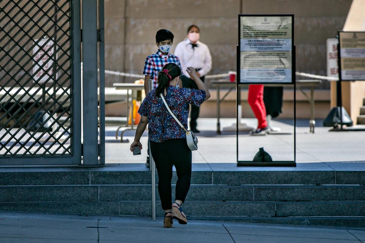 People wear masks outside the Cathedral of Our Lady of the Angels on Sunday.