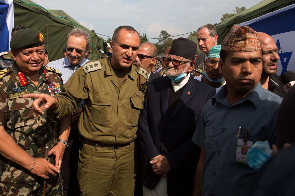 Nepal's Prime Minister Sushil Koirala (center right) is escorted by his chief of staff, Gaurab Shamser (left), as he is briefed by an Israeli officer (center left) during a visit to the Israeli field hospital in Kathmandu on April 29.