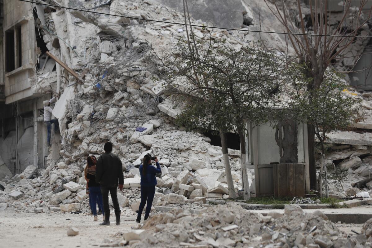 People stand near a building in Aleppo, Syria, that was destroyed in an earthquake.