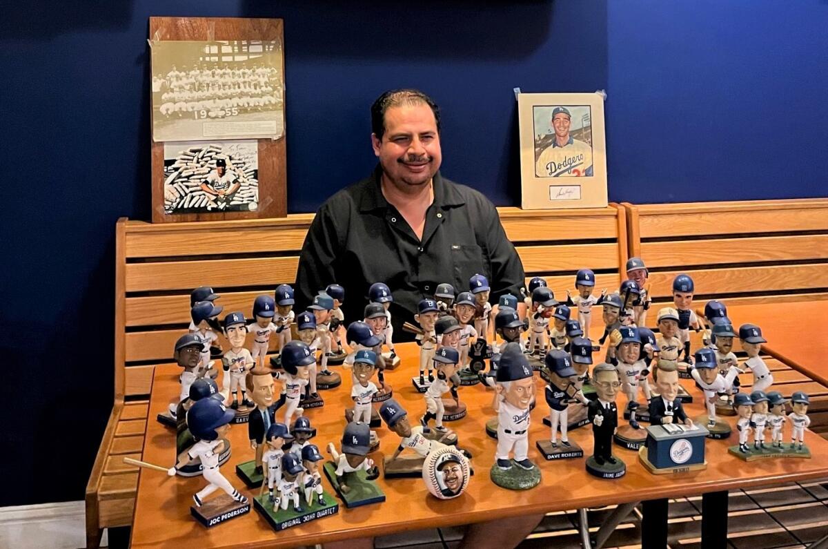 Juan Gomez sits in front of his Dodgers bobblehead collection displayed at his restaurant Penna Pasta in Lahaina, Hawaii