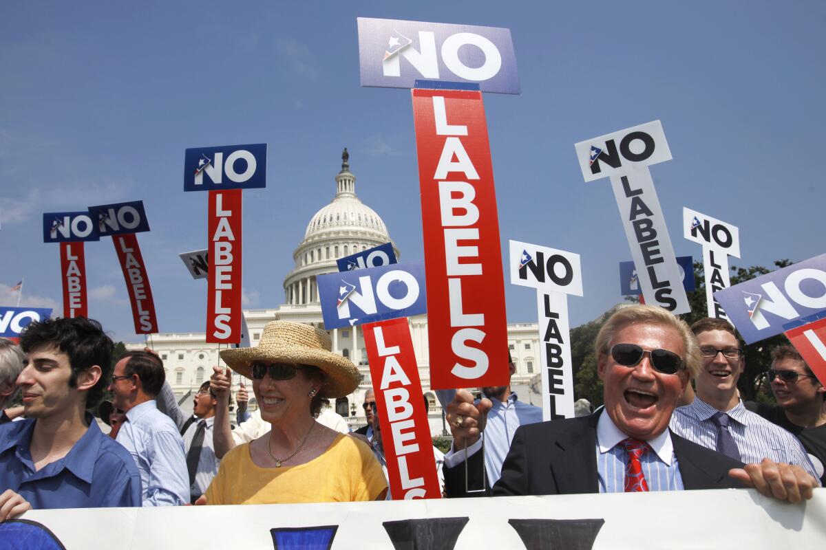 People rally outside the Capitol with signs reading "No Labels."