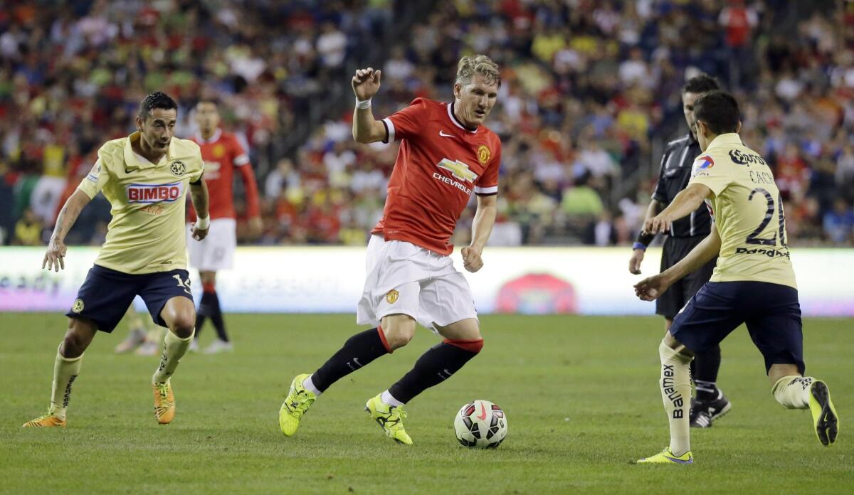 Bastian Schweinsteiger (c) del United escapa a la marca de Francisco Rivera (d) y Rubens Sambueza (i).
