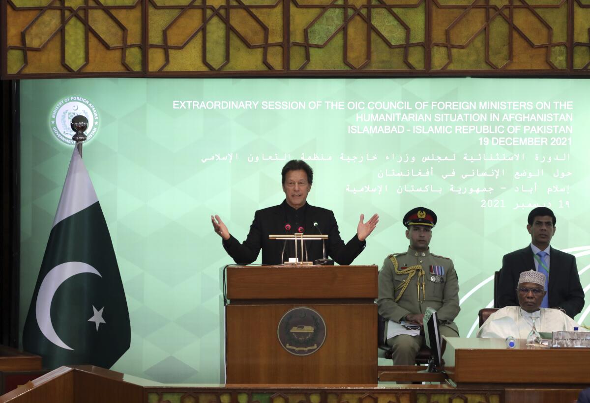 Pakistan Prime Minister Imran Khan speaks at a lectern and holds his arms out.