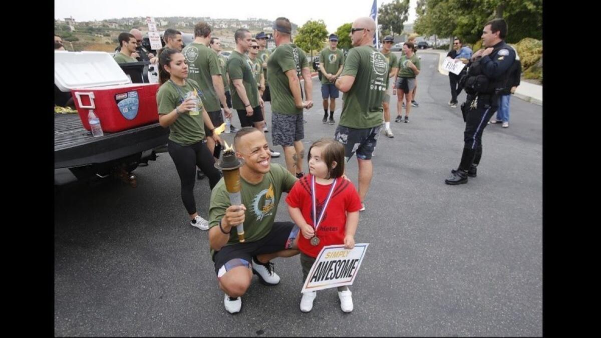 Laguna Beach police officer Jeremiah Kennedy greets Rocco Keller, 5, during the annual Law Enforcement Torch Run for Special Olympics Southern California on Thursday.