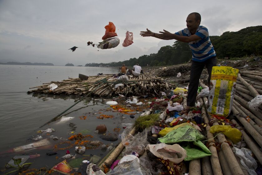 FILE - A Hindu devotee throws flowers and plastic bags into river Brahmaputra in Gauhati, India, Wednesday, Oct. 9, 2019. Negotiators from around the world gather at UNESCO in Paris on Monday, May 29, 2023, for a second round of talks aiming toward a global treaty on fighting plastic pollution in 2024. (AP Photo/Anupam Nath, File)