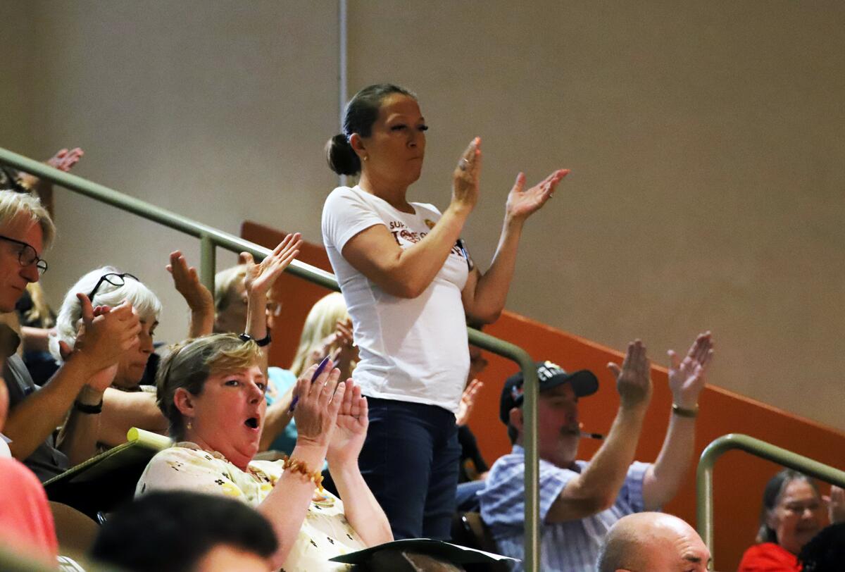 People cheer in support of Huntington Beach City Clerk Robin Estanislau as she speaks about the proposed charter amendments.