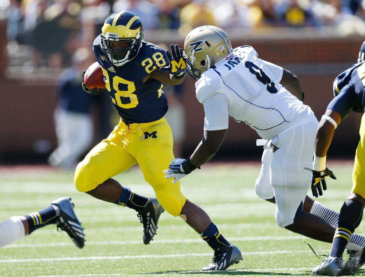 Michigan's Fitzgerald Toussaint, left, tries to stiff-arm Akron's C.J. James during the first quarter of the Wolverines' narrow win on Saturday.
