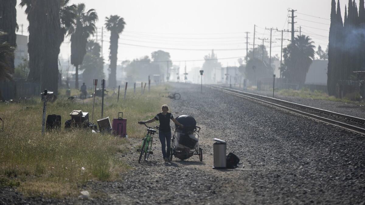 A homeless woman walks along the railroad right-of-way after Los Angeles police officers order homeless people out of an encampment in Chatsworth in April.