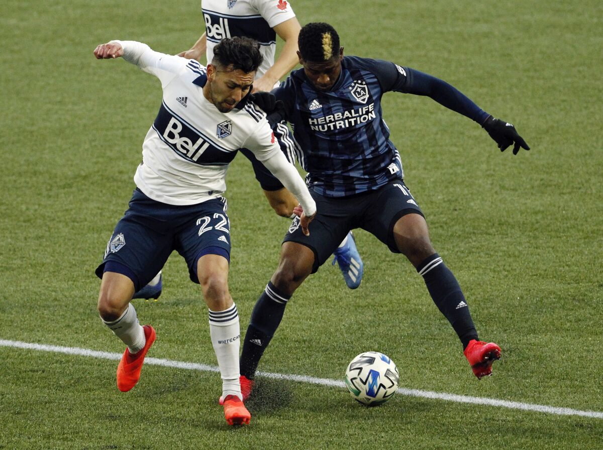 Vancouver Whitecaps defender Erik Godoy, left, and Los Angeles Galaxy midfielder Yony Gonzalez battle for possession during the first half of an MLS soccer match in Portland, Ore., Sunday, Nov. 8, 2020. (AP Photo/Steve Dipaola)