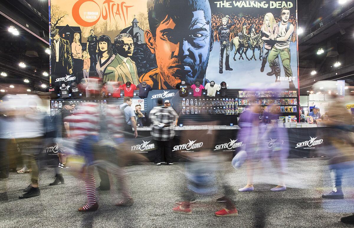 WonderCon attendees walk past "The Walking Dead" booth at WonderCon 2016 at the Los Angeles Convention Center.