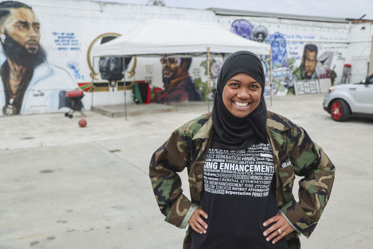 Gabby Hines poses for photos next to murals in the Encanto neighborhood