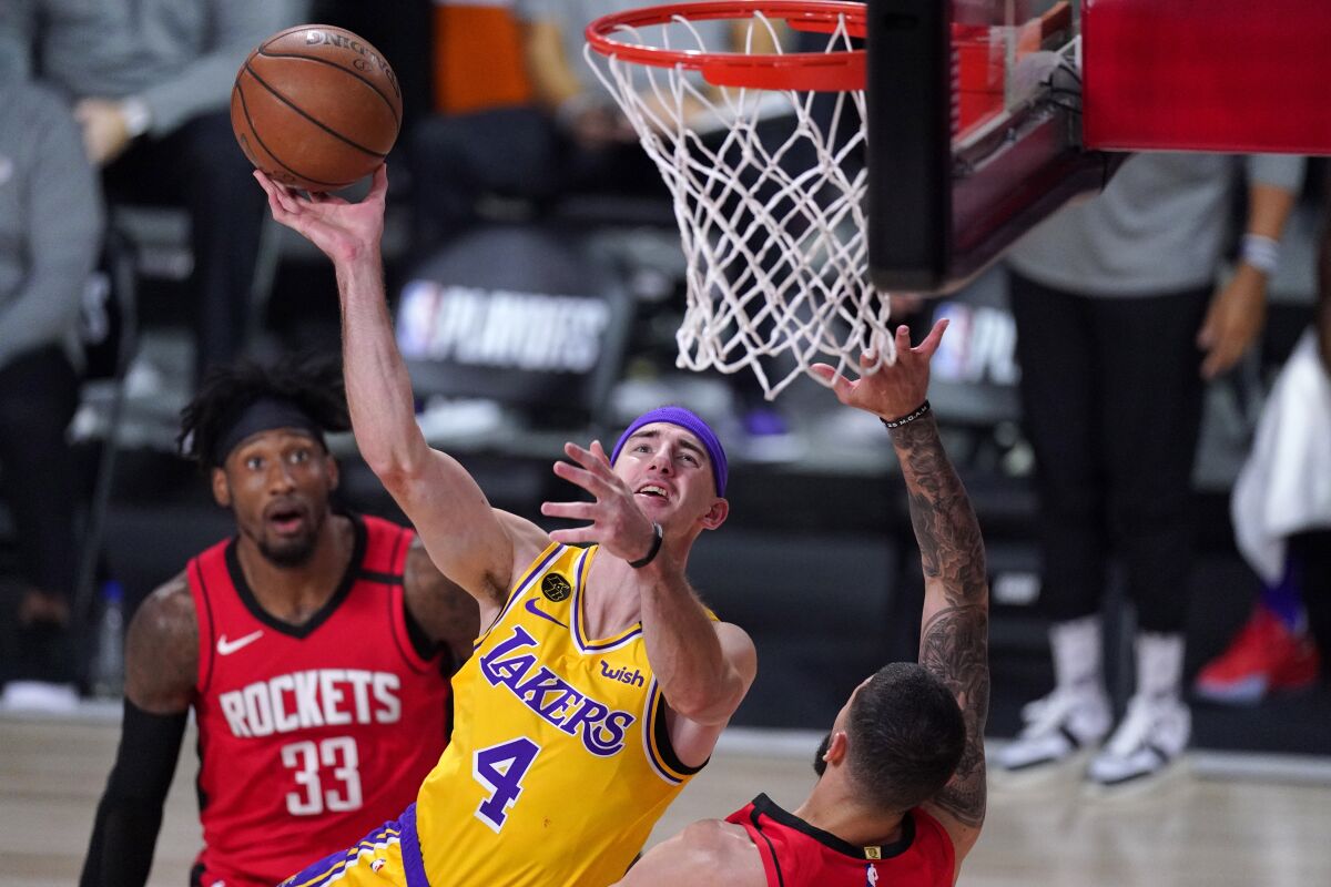 Los Angeles Lakers' Alex Caruso (4) goes up for a shot as Houston Rockets' Austin Rivers, right, defends.